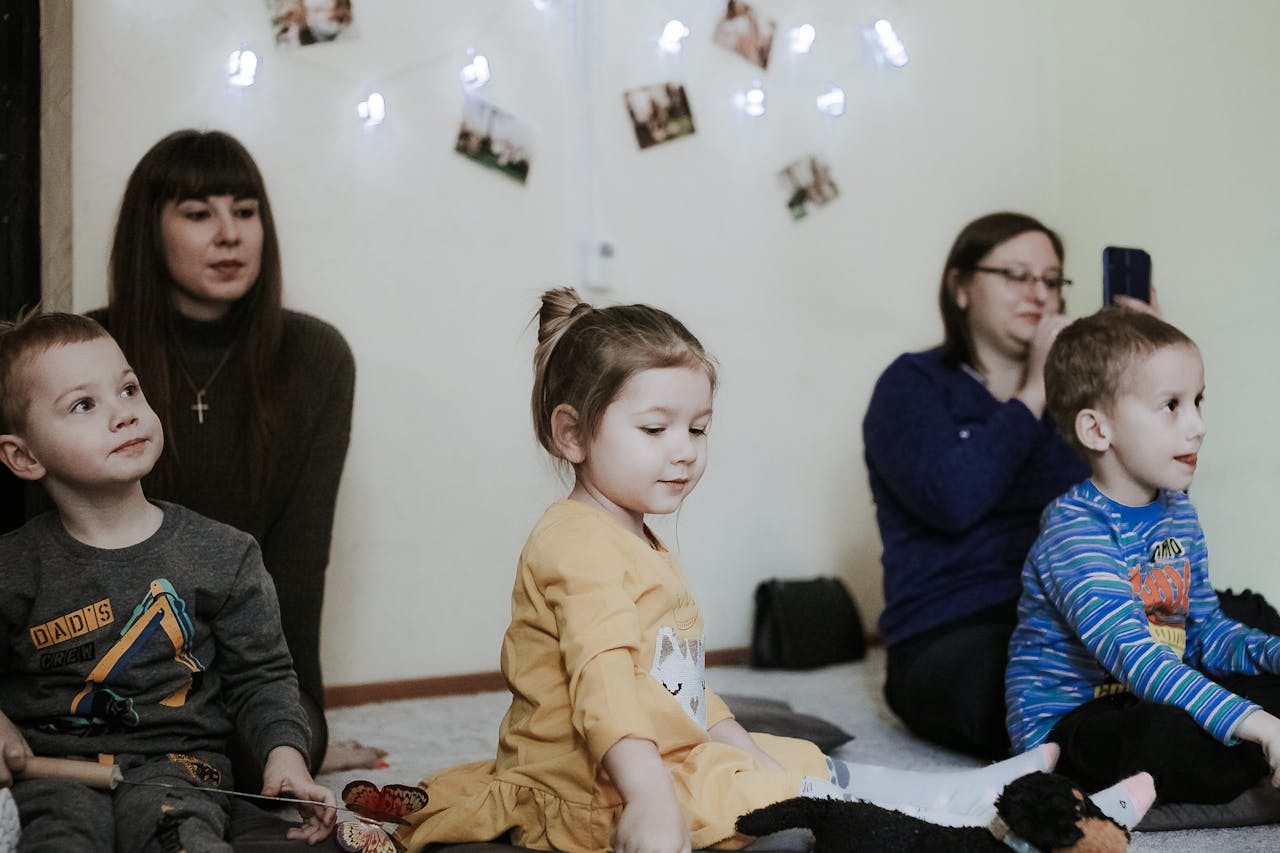 Group of young children engaged in an indoor educational activity with adult supervision.