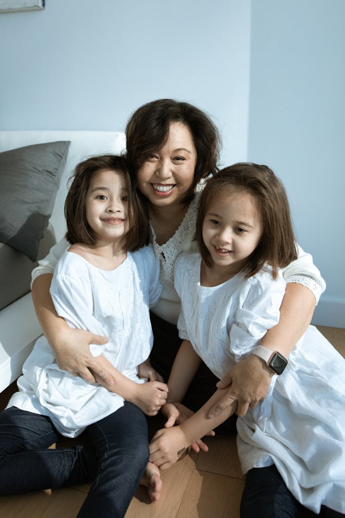 A joyful mother hugging her two daughters in a cozy indoor setting.