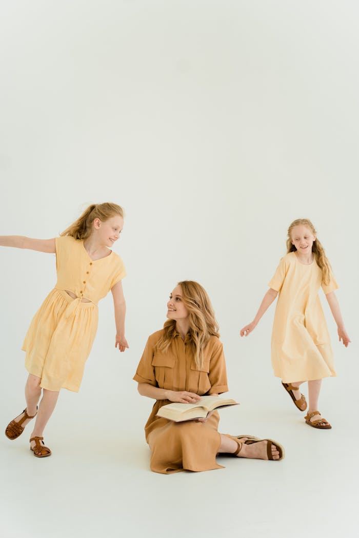 A mother with her two daughters enjoying a playful moment in a studio setting.
